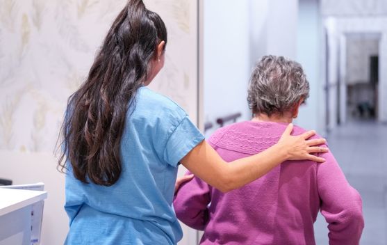 Aide-soignante qui aide une résidente en EHPAD à se déplacer